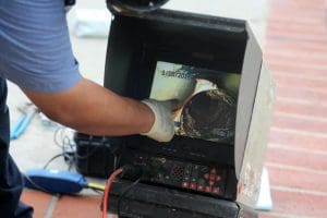 A man conducting drain surveys with CCTV equipment on a sidewalk.