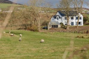 A luxury, white rural house set in scenic fields.